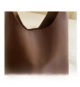Macro shot of brown leather tote bag showing high-quality stitching and matte texture