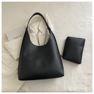 Detail shot of black leather tote bag set with matching small zipper pouch on desk