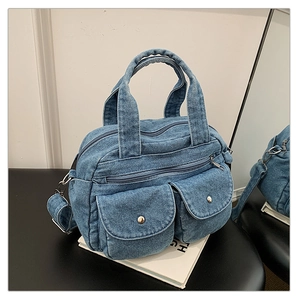 Detail of vintage denim crossbody bag showing metal snap buttons and double zippers