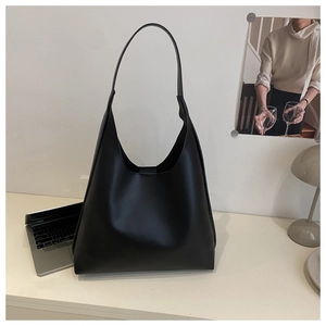 Minimalist black hobo shoulder bag shown in a professional home office desk setting