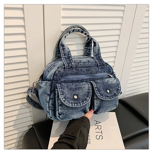 Detail of vintage blue denim crossbody bag with dual buttoned pockets and top handles