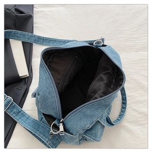 Detail of blue denim crossbody bag interior featuring black lining and zipper pocket