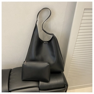 Detail of minimalist black faux leather tote with matching zippered inner pouch