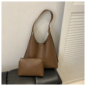 Detailed view of brown leather tote bag set with matching inner pouch on a chair