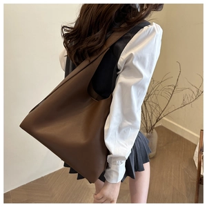 Large dark brown matte leather tote bag styled on shoulder with minimalist aesthetic