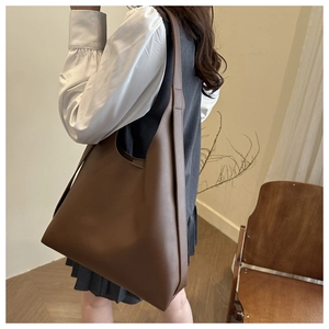 Detail of dark brown large capacity shoulder bag shown on a model in a warm room