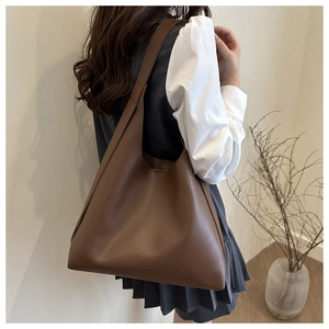 Detail view of a large brown minimalist tote bag showing matte leather texture and capacity