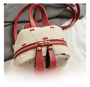 Detail of red zipper and gold-tone hardware on mini backpack with bow patterns