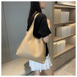 Model wearing a beige large capacity tote bag showing shoulder strap and side profile
