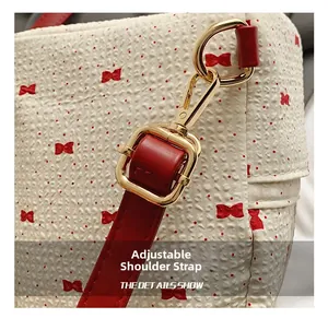 Detail of adjustable red leather shoulder strap with golden metal lobster clasp and buckle