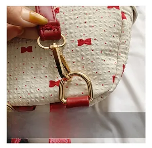 Detail of premium gold metal hooks and red leather trim on a polka dot backpack