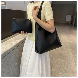 Detail of minimalist black large tote bag and matching zipper clutch in soft leather