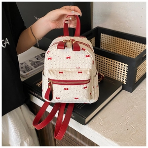 Detail of mini cream backpack with red bow print and woven texture front pocket