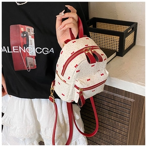 Close-up of white woven mini backpack featuring red bow prints and leather trim details