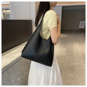 Minimalist black large hobo bag styled on a model in a modern corridor scene
