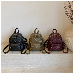Detailed shot of mini quilted backpacks in black, olive green, and burgundy faux leather