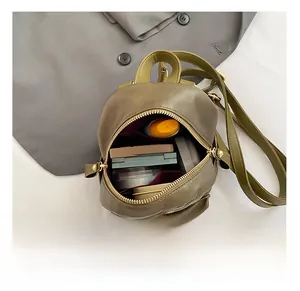 Detail view of mini olive green backpack interior with cosmetics and gold zippers