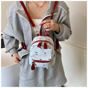 Detailed macro of white textured mini backpack with red bow patterns and leather straps