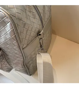 Close-up of metallic silver woven bag featuring glossy hardware and white nylon strap