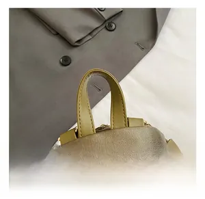 Detail of dark green textured leather backpack featuring gold-tone hardware and handle