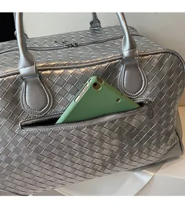 Macro detail of silver woven tote featuring back zipper pocket holding a tablet