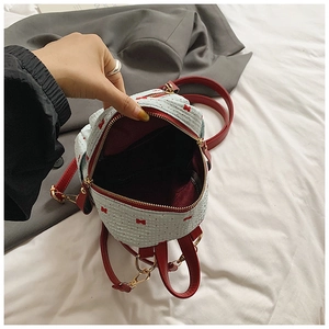Close-up of mini backpack showing red bow detail, polka dot print, and spacious red lining