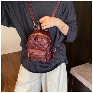 Detail view of burgundy quilted mini backpack with gold hardware and PU leather texture
