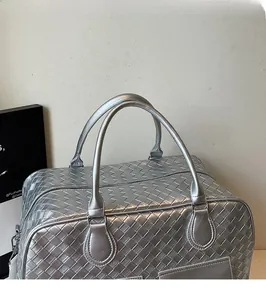Detailed view of silver woven Boston bag with smooth rounded handles and metal rings