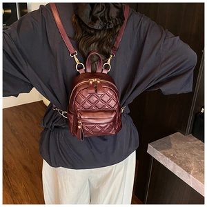Detail of wine red quilted leather backpack featuring premium diamond pattern and gold zipper