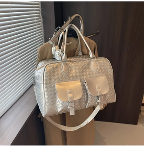 Macro detail of silver woven leather tote with metallic finish and front buckle pockets
