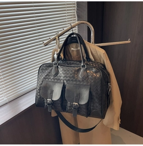 Close-up of black woven leather duffel bag with two buckle pockets and top handles