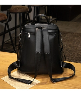 Detailed rear view of black pebble leather backpack featuring adjustable straps and zipper pocket