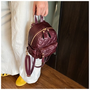 Detail of burgundy PU leather mini backpack with quilted pattern and golden zipper