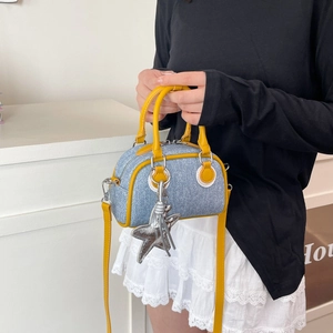 Sac Boston en denim bleu avec bordure en cuir jaune et pendentif étoile argent