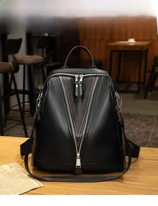 Detail of black pebbled leather backpack with V-shaped zipper and contrast stitching