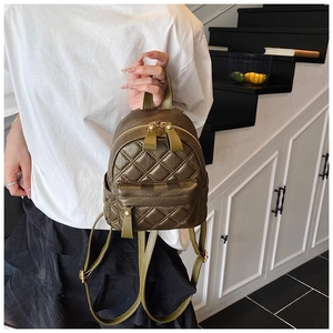 Detail showing olive green quilted mini backpack with golden hardware and hand-held strap