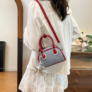 Sac Boston en jean tendance avec garniture en cuir rouge porté par un mannequin chic
