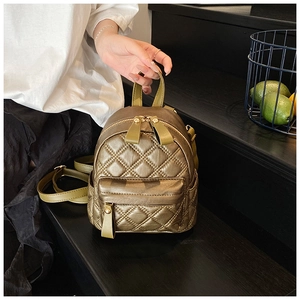 Detail of quilted metallic gold mini backpack with contrast green leather handle and straps