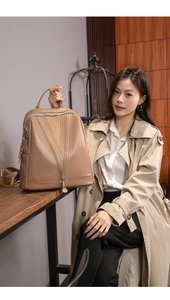 Detail of khaki leather backpack with V-shaped zipper design on beige trench coat outfit