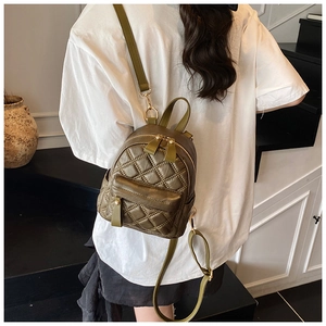 Olive green quilted mini backpack on model showing stylish rhombus pattern and scale