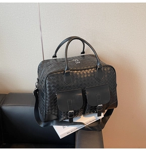 Detail view of woven texture duffel bag with front buckle pockets and adjustable strap