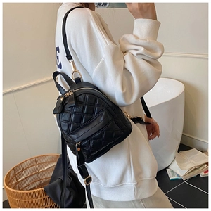 Detail of black quilted leather backpack with gold zippers shown in a casual lifestyle setting