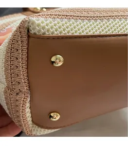 Close-up of woven bucket bag bottom featuring protective gold-tone metal feet and leather