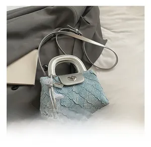 Close-up of heart-shaped metal clasp on light blue quilted denim mini handbag