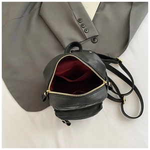 Detail of fashion quilted mini backpack showing red fabric lining and gold-tone zippers