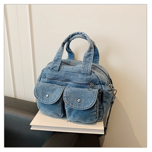 Detailed view of blue denim crossbody bag featuring utility pockets and metallic snaps