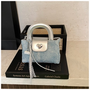 Detail of blue denim mini bag featuring a silver heart lock and white lace ribbon