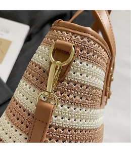 Detailed close-up of woven bucket bag featuring gold metal hook and striped texture