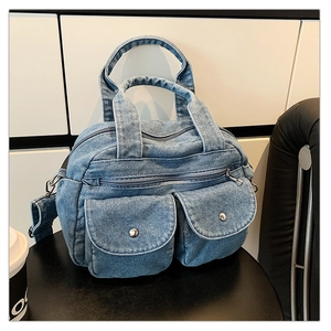 Detail view of denim crossbody bag showing multi-pockets and metal snap buttons