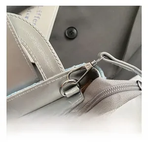 Detail of silver leather and blue denim patchwork bag featuring metal buckle and zipper closure